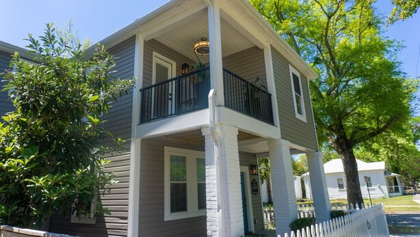 A two-story house with a balcony, white trim, and a small porch area. - Quiet Historic Retreat - 15 minutes from Riverwalk (Wilmington)