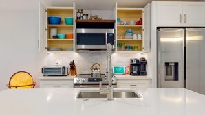 A modern kitchen with white cabinetry, a stainless steel refrigerator, a microwave, a coffee maker, and a kettle. - Quiet Historic Retreat - 15 minutes from Riverwalk (Wilmington)