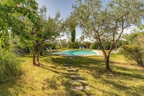 A swimming pool surrounded by trees and grass.