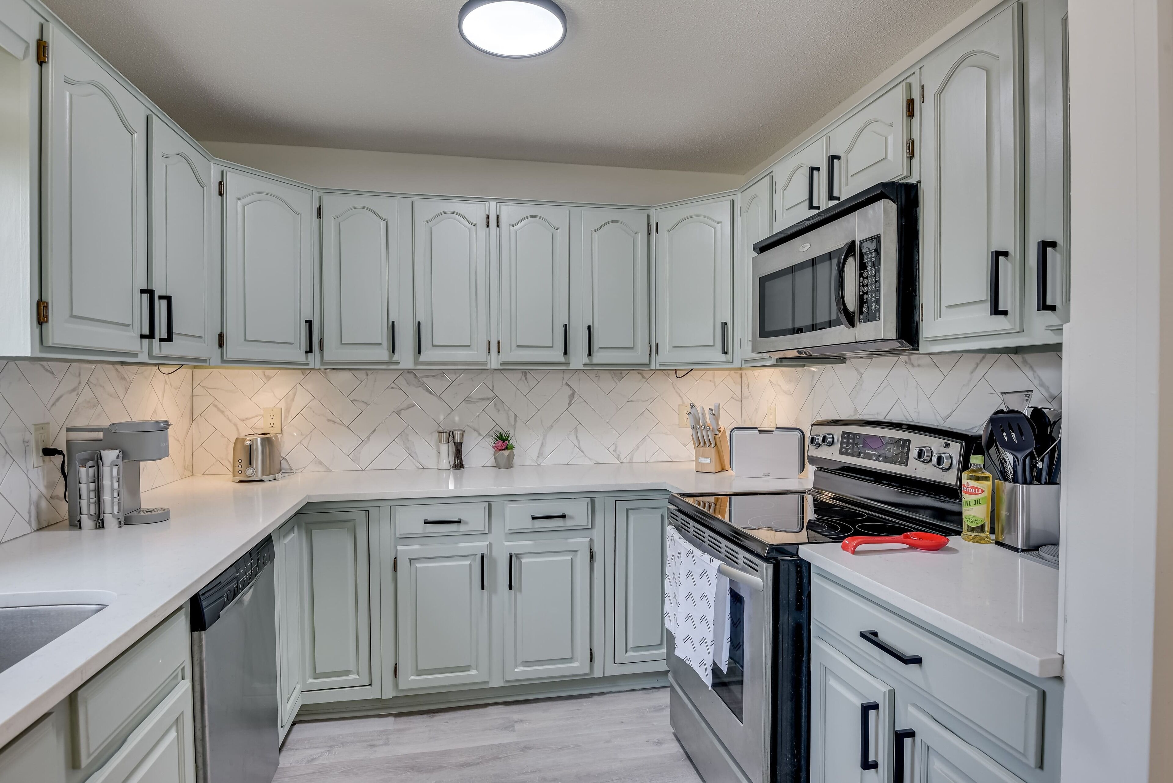 A kitchen with white cabinets, a microwave, an oven, and a dishwasher.