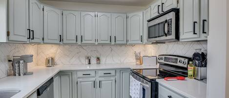 A kitchen with white cabinets, a microwave, an oven, and a dishwasher.