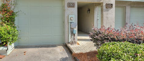 A building with two garage doors, numbered 110 and 112, and a utility box near the entrance.
