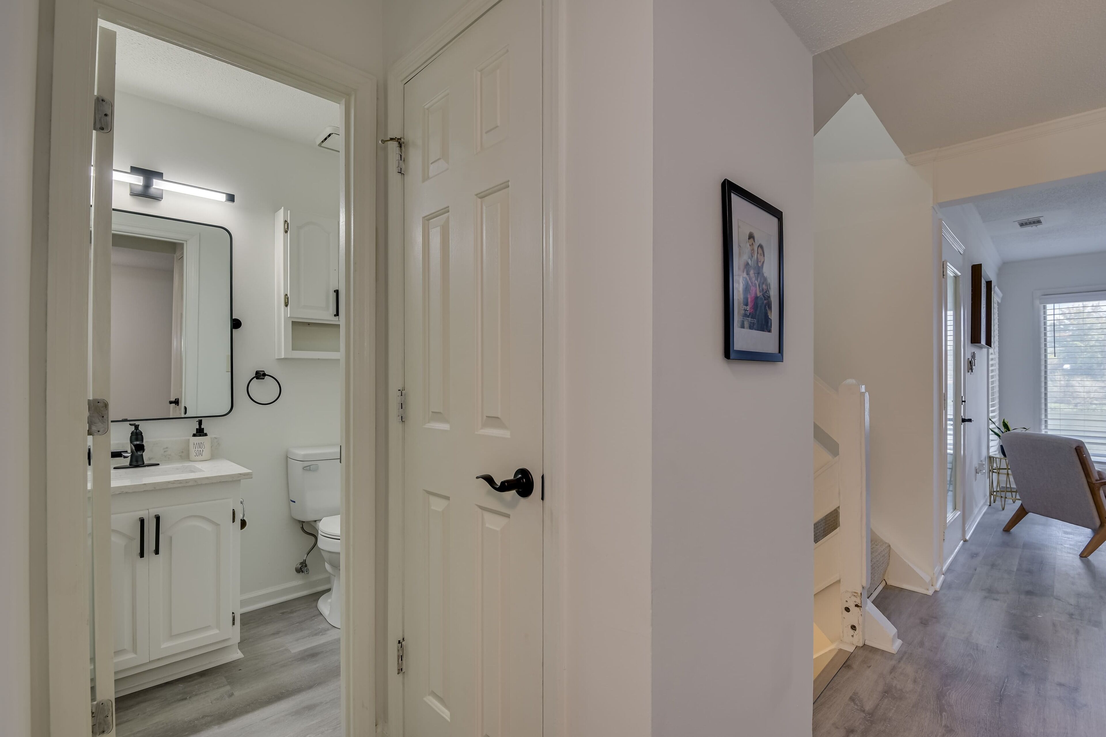 Een moderne badkamer met witte sanitair, een grote spiegel en een toilet.