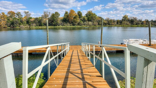 A wooden pier leading to a dock with boats, surrounded by trees and a calm lake. - Beautiful 3BR Townhouse (Augusta)
