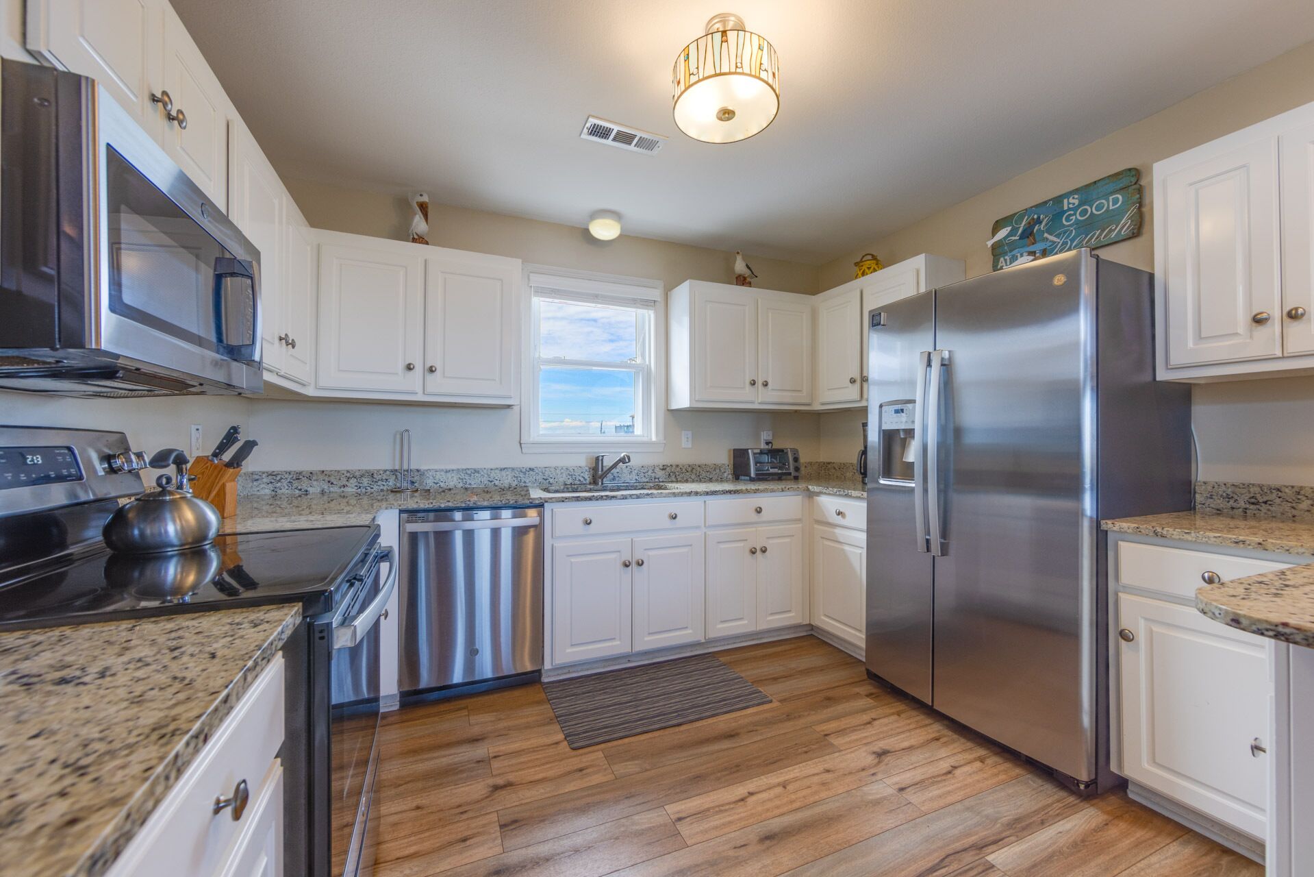 A modern kitchen with white cabinets, stainless steel appliances, and a granite countertop.