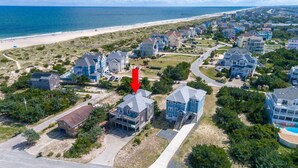 Vue aérienne d’une zone résidentielle côtière, avec des maisons, une plage et une jetée.