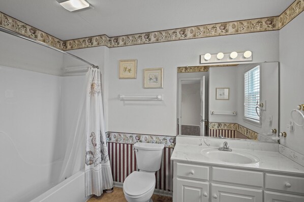 A bathroom with a bathtub, a toilet, a sink, and a mirror. - Semi-Oceanfront Home in Avon with Hot Tub, Smart TVs, and Basketball Hoop (Avon)