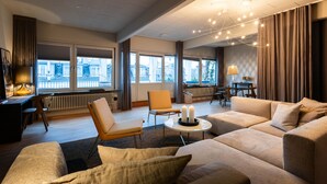 Una sala de estar moderna con un conjunto de sofás, un comedor y ventanas amplias que ofrecen vistas de la ciudad.