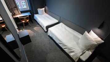 Habitación de hotel con dos camas individuales, un escritorio y una silla.