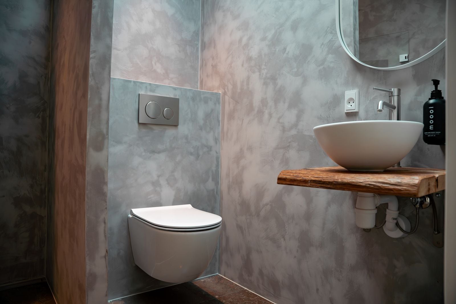 A modern bathroom with a toilet, a sink, and a mirror.