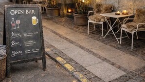 Zona de estar al aire libre con un cartel que anuncia vinos, cervezas y licores disponibles.