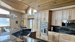 A modern kitchen with wooden cabinets, a granite countertop, and a built-in oven. - Experience the Magic of Wapiti Valley in Luxury. Stunning Views-East Yellowstone (Cody)