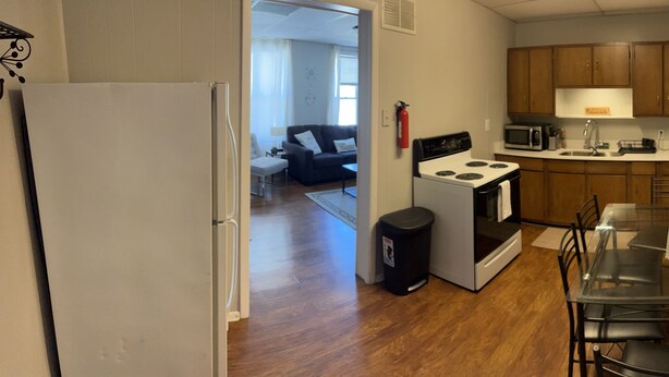 A compact kitchen with a stove, microwave, and a dining area with a glass table and chairs. - Downtown Getaway 2 (Michigan City)