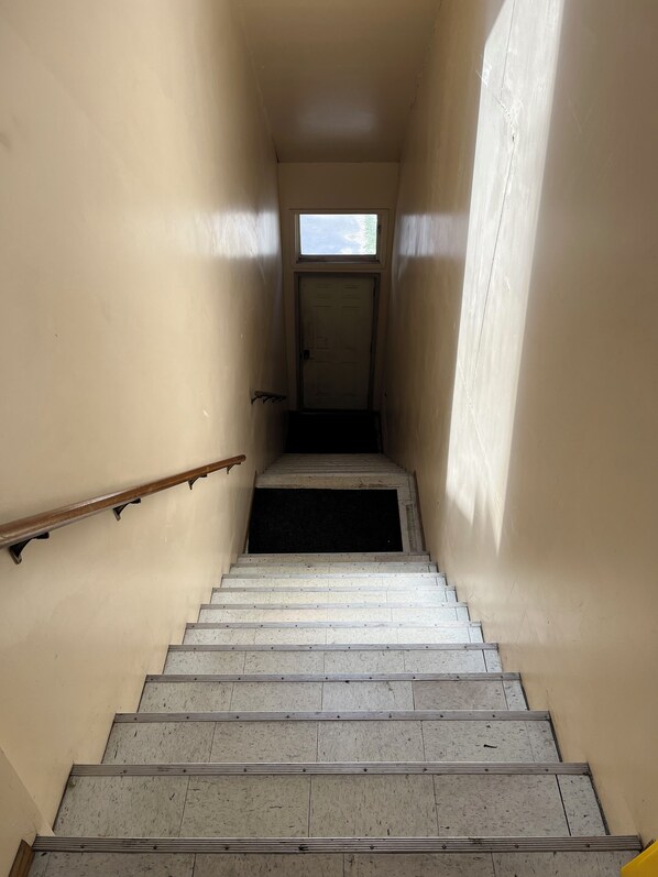 A narrow stairway with a handrail, leading to a door at the top.