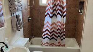 A bathroom with a bathtub, toilet, sink, and towel rack. - Downtown Getaway 2 (Michigan City)