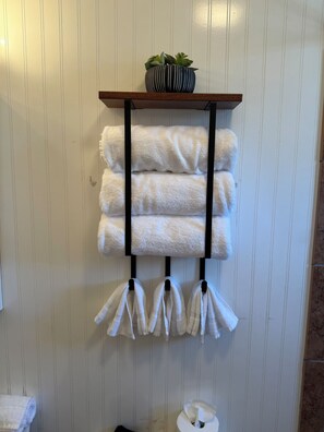 A towel rack with folded towels and a potted plant. - Downtown Getaway 2 (Michigan City)