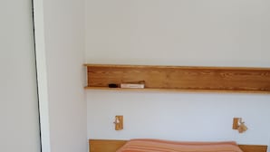 Un dormitorio con cama, cabecera de madera y manta a rayas.