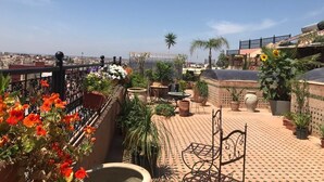 Terraço no telhado com plantas em vasos, móveis de exterior e vista ampla da paisagem urbana.