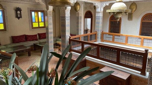 Interior com arcos elaborados, um banco de madeira e piso estampado.