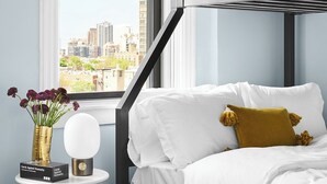 Un dormitorio moderno con una cama litera, una mesita de noche con un florero y una tarjeta, y una alfombra estampada.