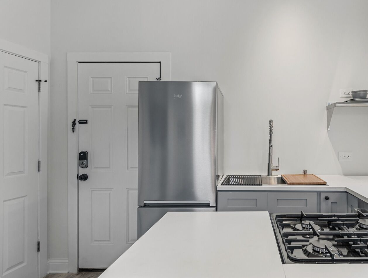 A kitchen with a stainless steel refrigerator, a gas stove, and a white countertop.