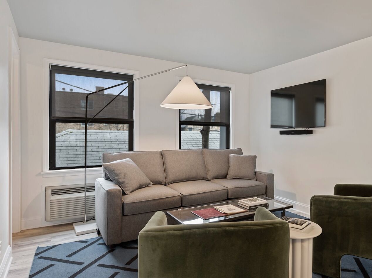 A modern living room with a sofa, a coffee table, and a TV mounted on the wall.