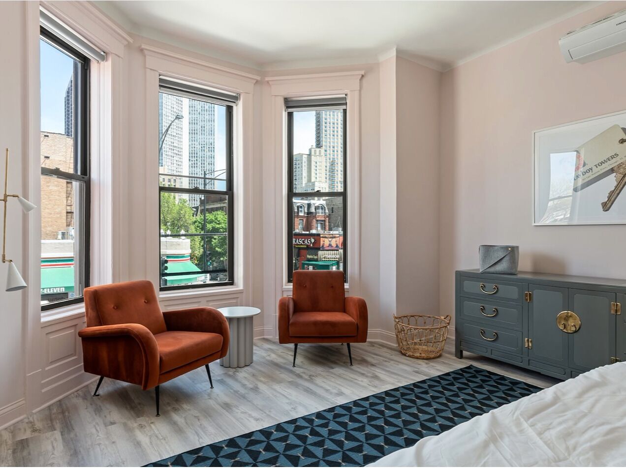 A room with two armchairs, a small round table, a grey cabinet, and a bed.