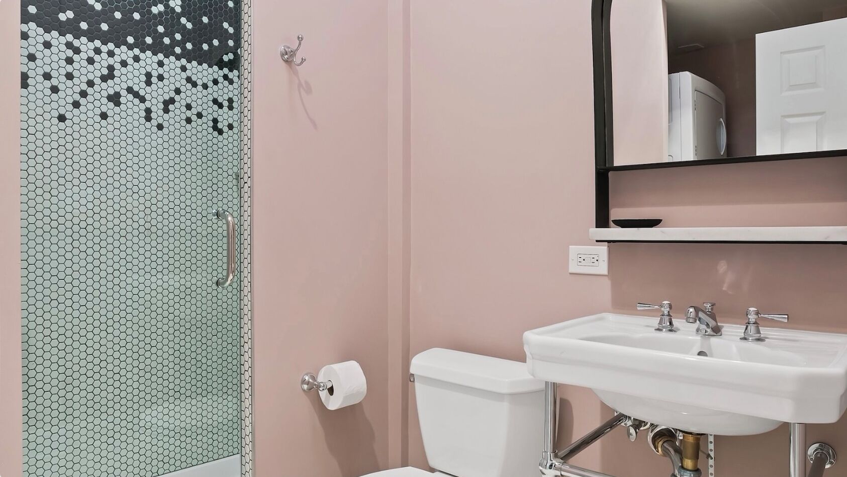 A bathroom with a toilet, sink, and a mirror above the sink.