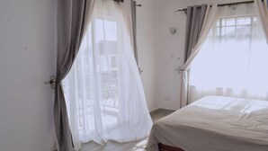 Ein Schlafzimmer mit Bett, Vorhängen und Blick nach draußen.