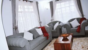 Ein Wohnzimmer mit zwei grauen Sofas, einem Holztisch und einem gemusterten Teppich.