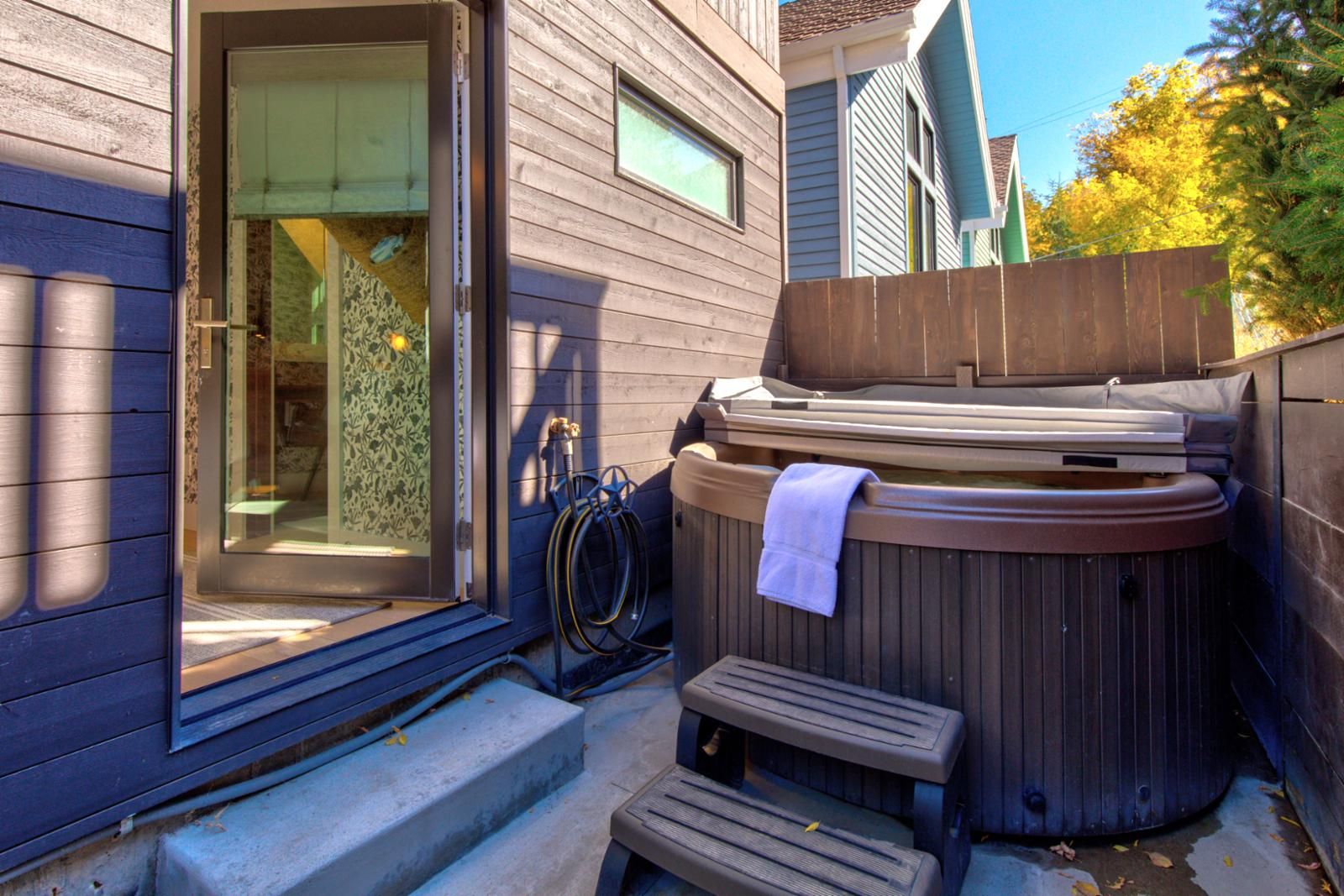 A hot tub with a towel, a hose, and steps leading to a door.