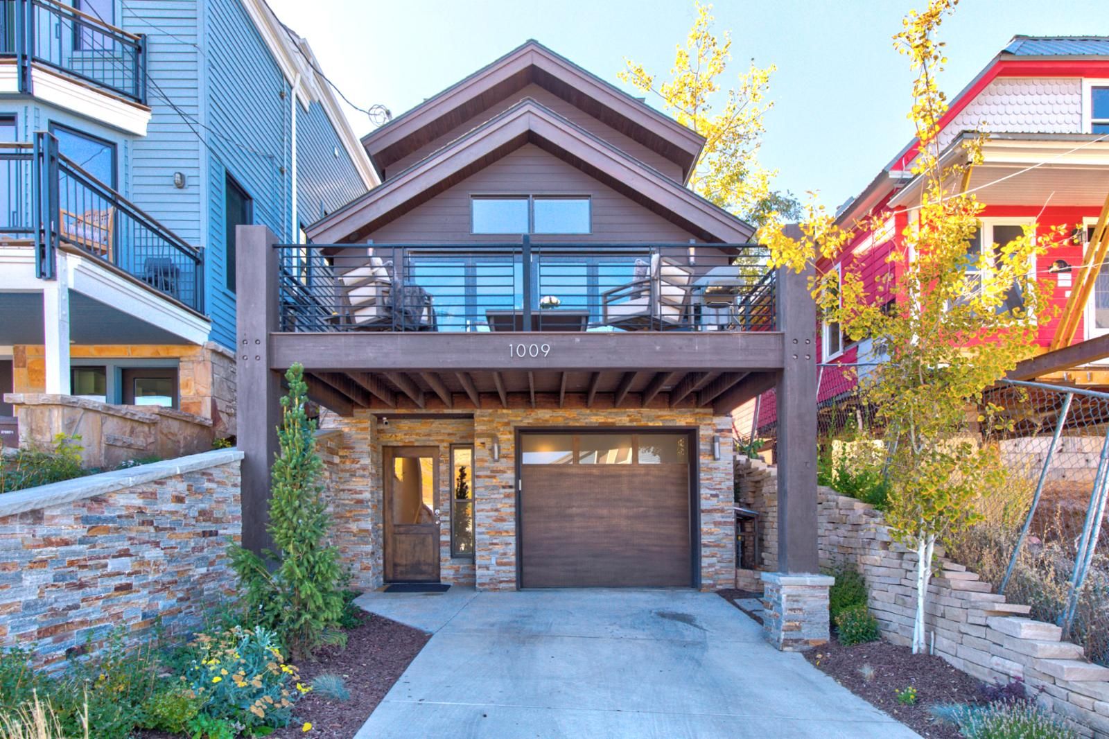 A modern two-story house with a stone facade, a garage, and a balcony.