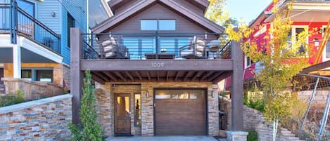 A modern two-story house with a stone facade, a garage, and a balcony.