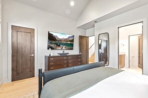 Une chambre à coucher avec un lit, une commode, une télévision et une vue sur un lac de montagne.