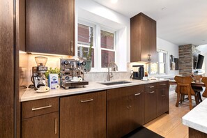 Eine moderne Küche mit dunklen Holzschränken, einer Kaffeemaschine und einer Wand mit Steinakzenten.