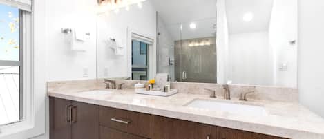 A modern bathroom with two sinks, a large mirror, and a vanity with drawers.