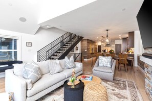 Een moderne woonkamer met een trap, een eethoek en een keuken.