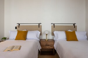 A double bed with a book on it, two nightstands with lamps, and a small plant on the left.