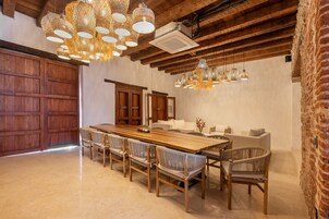 A spacious dining area with a long wooden table, wicker chairs, and hanging wicker chandeliers.