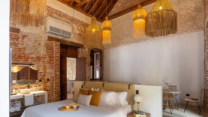 Een slaapkamer met een groot bed, een houten nachtkastje, een nachttafeltje en een hanglamp.