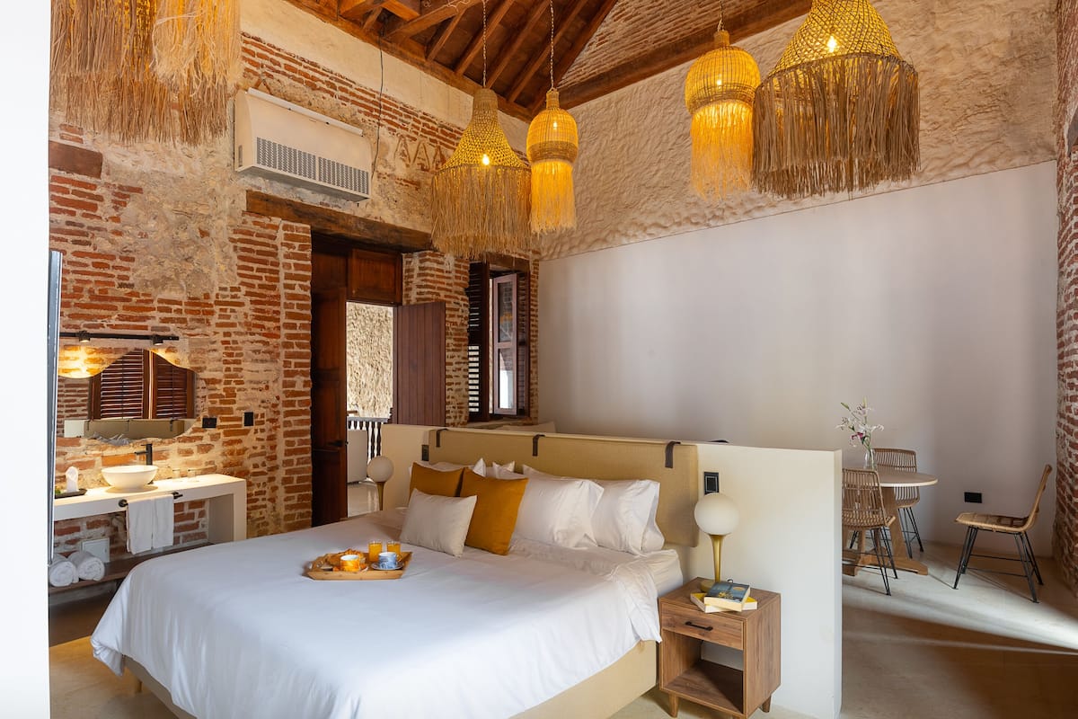 Une chambre à coucher avec un grand lit, une table de chevet en bois et une lampe suspendue.