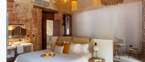 A bedroom with a large bed, a wooden nightstand, a bedside table, and a hanging light fixture.