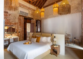 Un dormitorio con una cama grande, una mesita de noche de madera, una mesilla auxiliar y una lámpara colgante.