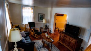 Una sala de estar con sofá, sillas, una mesa de centro, televisor y aparador.