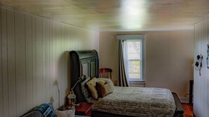 Un dormitorio con cama, sofá, alfombra, ventana y lámpara en el techo.