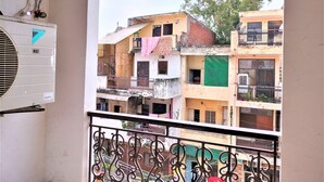 Vista desde un balcón con baranda de metal, sobre una hilera de edificios de varios pisos con balcones, algunos con ropa tendida.