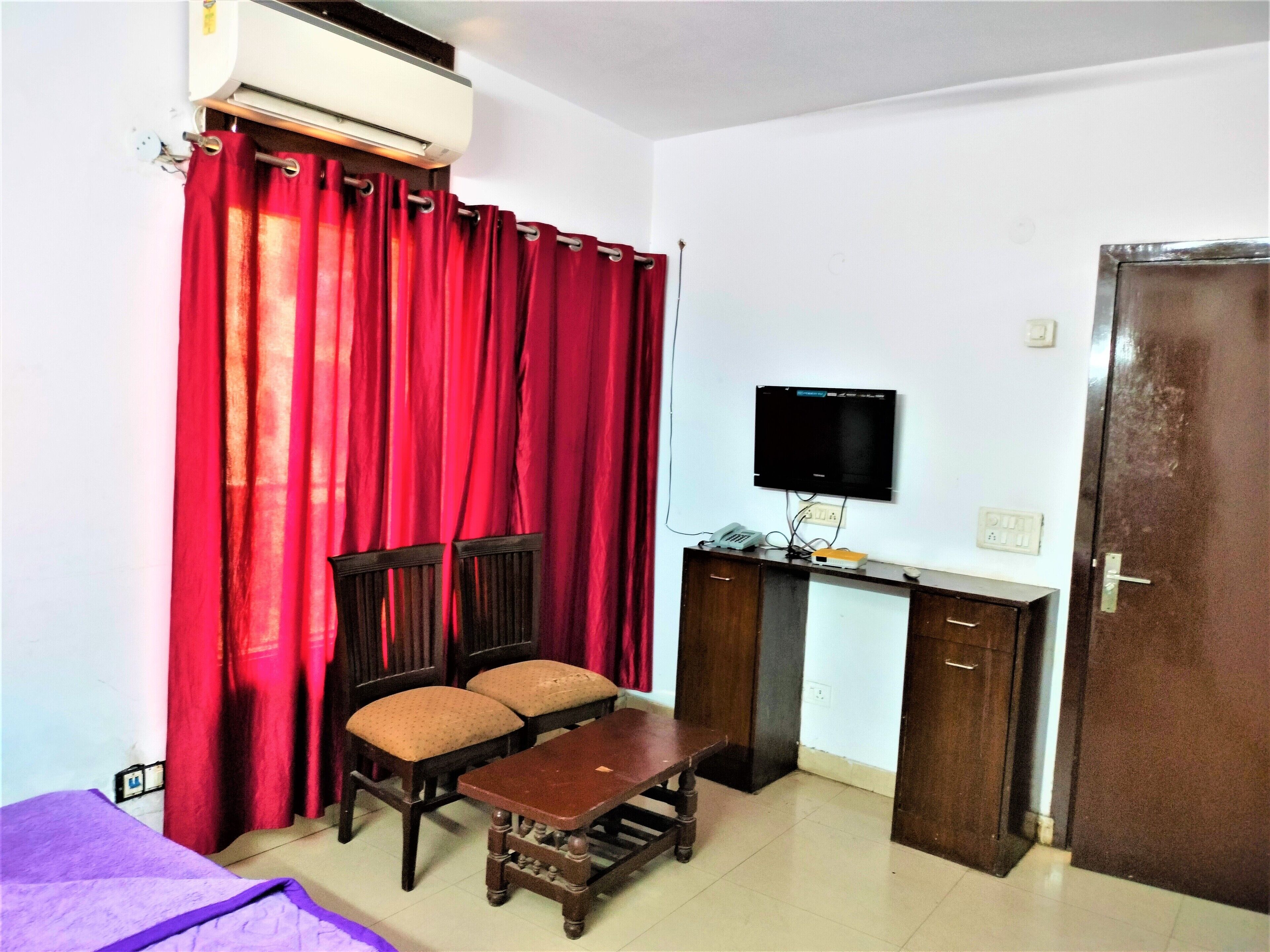 A room with a bed, a desk with a computer, a TV, and a chair.