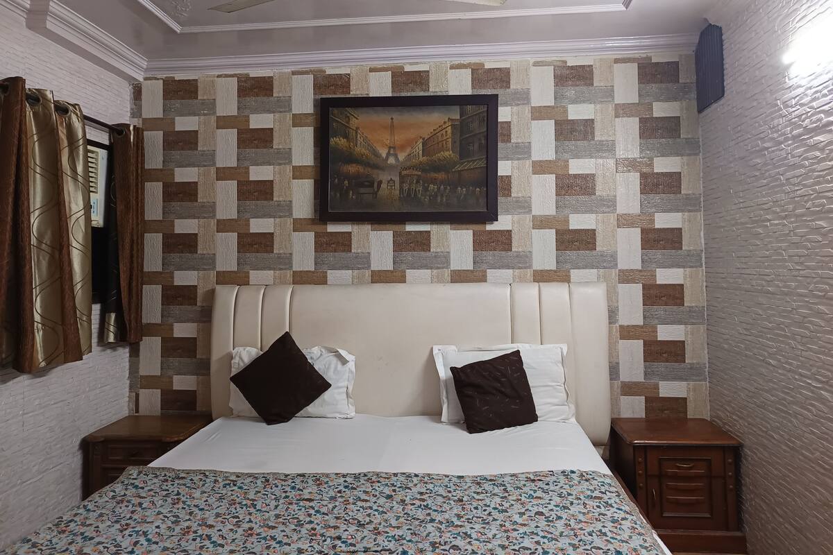 A bedroom with a bed, two nightstands, a ceiling fan, a patterned wall, and a framed picture.