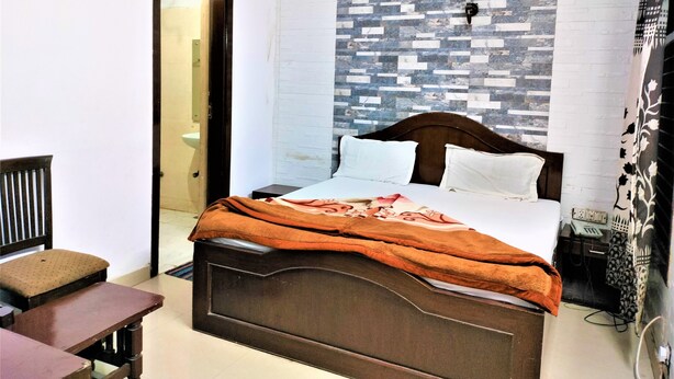 Un dormitorio con una cama, una mesita de noche de madera, una silla y una pared con diseño decorativo.