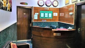 Zona de recepción con mostrador de madera, varios relojes, certificados enmarcados y un cartel de 'No Fumar'.